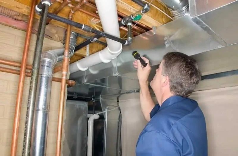 Tekniker inspekterar rör och ventilationskanaler i ett bjälklag